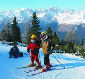 children on ski run - background Brenta - Credit - APT Dolomiti di Brenta - Altopiano della Paganella